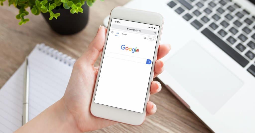 Person holding a phone displaying Google search page